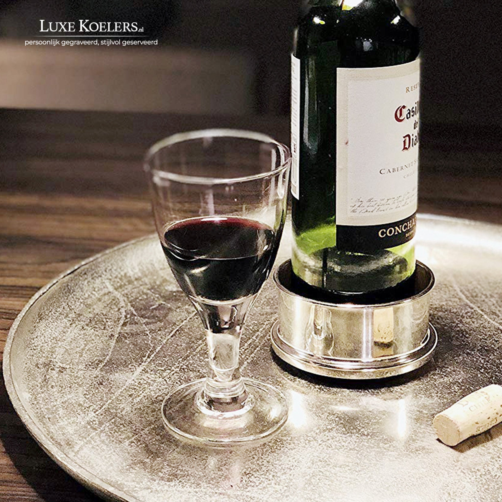 Zilveren wijn onderzetter met een glas en fles wijn op een zilveren dienblad