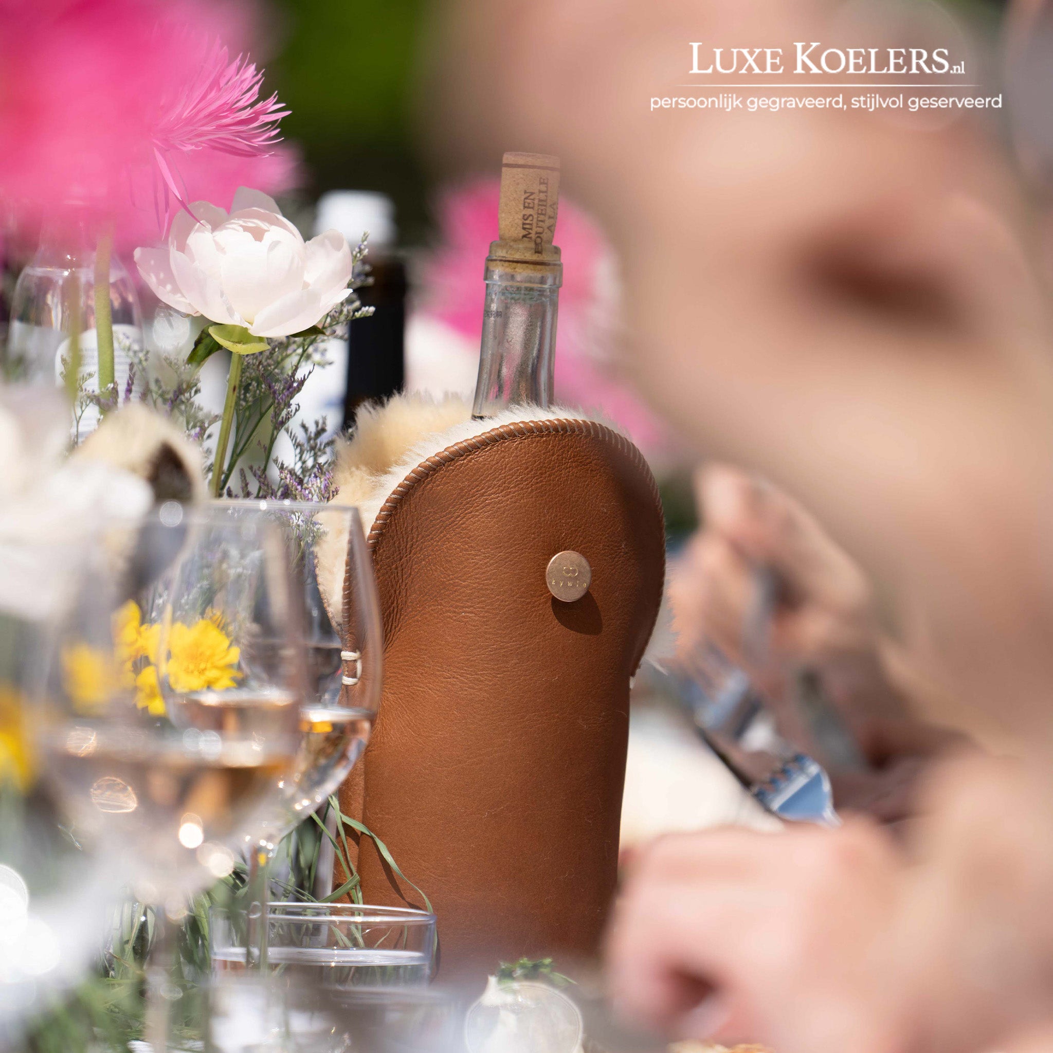 Kywie model Tulip voor wijn en normale champagne flessen.De wijnkoeler is volledig gemaakt van natuurlijke schapenvacht. Koeler met fles op tafel met glazen en bloemen