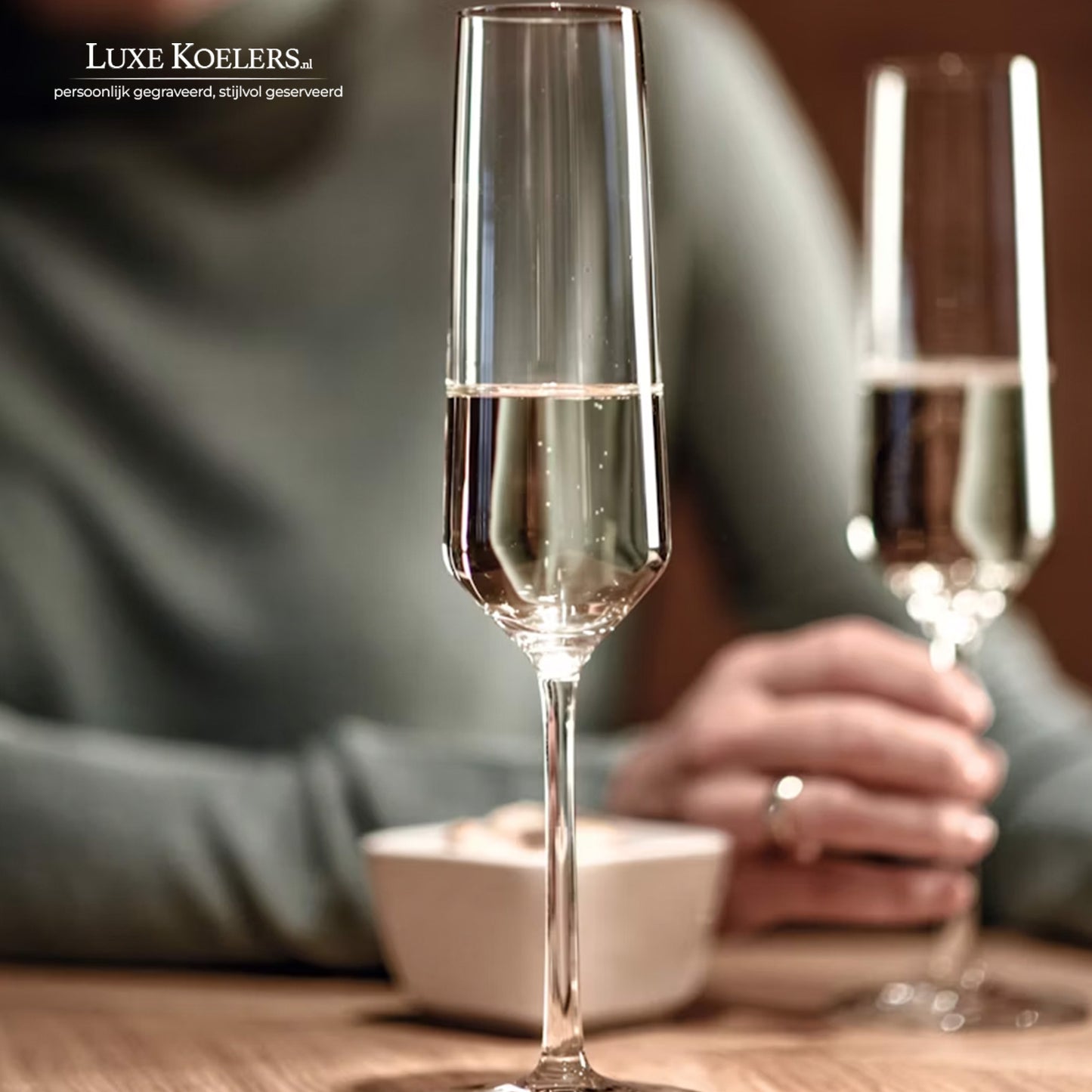 champagneglas pure op tafel en op vage achtergrond hand met ring