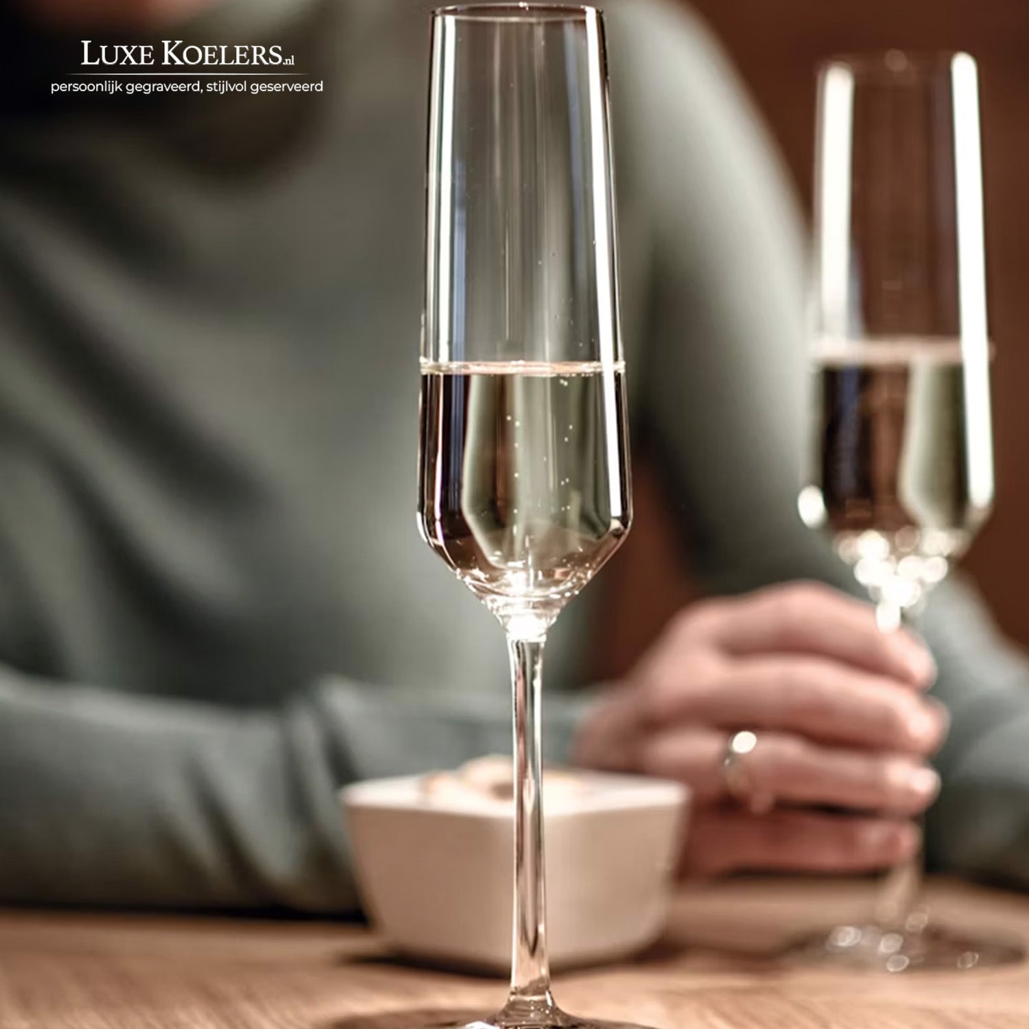 champagneglas pure op tafel en op vage achtergrond hand met ring