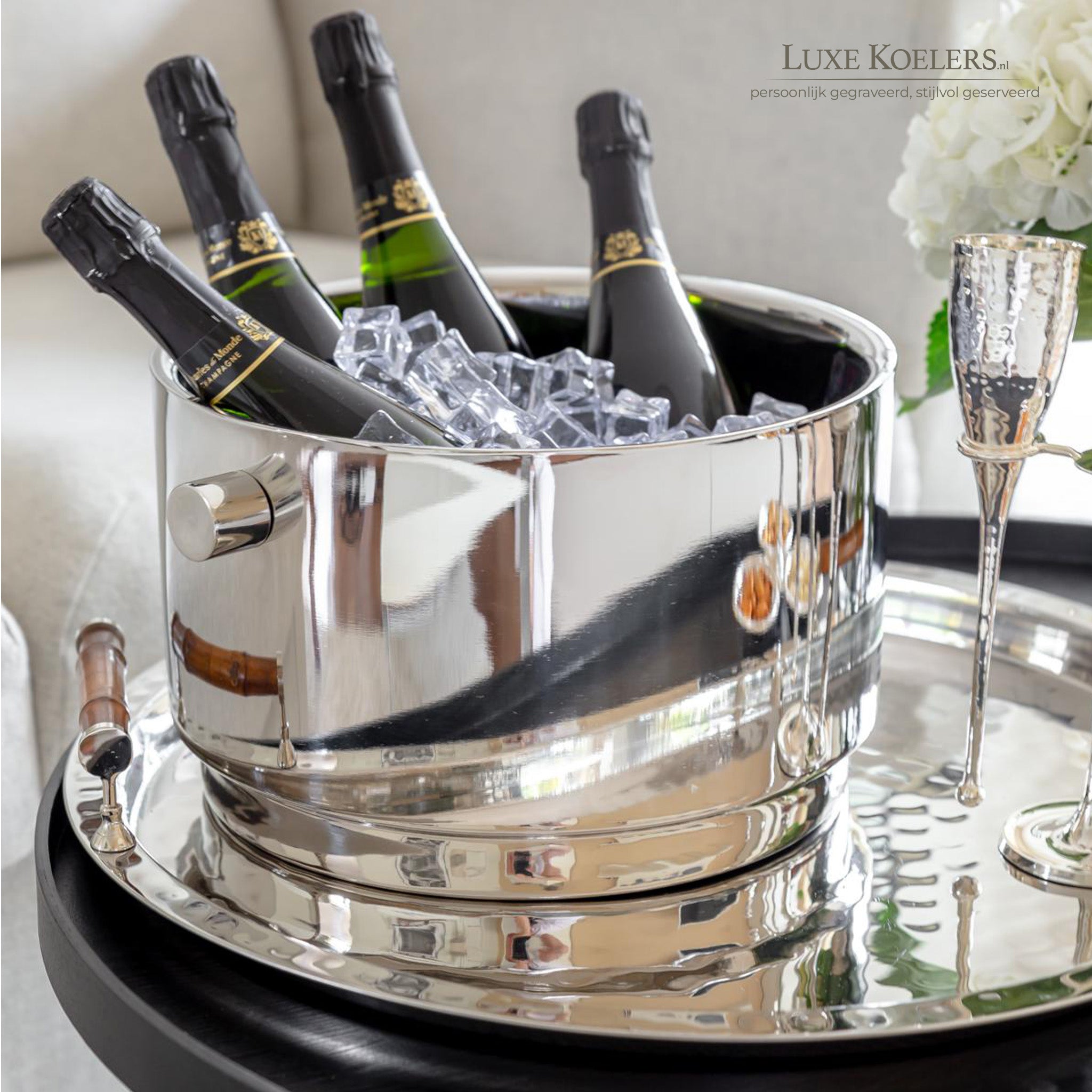 vier champagneflessen in een zilveren koeler op een zilveren dienblad