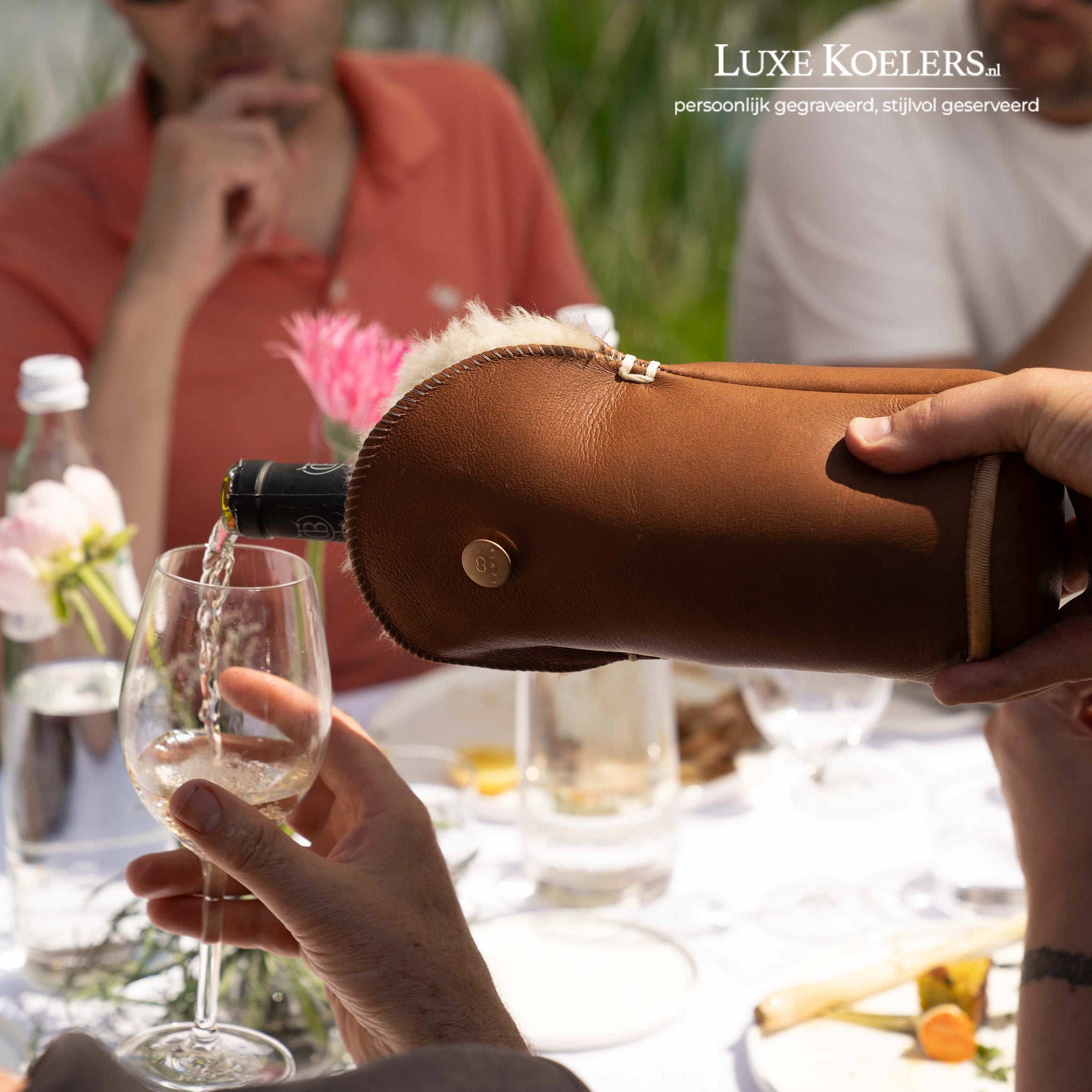 Kywie model Tulip voor wijn en normale champagne flessen.De wijnkoeler is volledig gemaakt van natuurlijke schapenvacht. Koeler met fles in schenkende positie aan tafel.