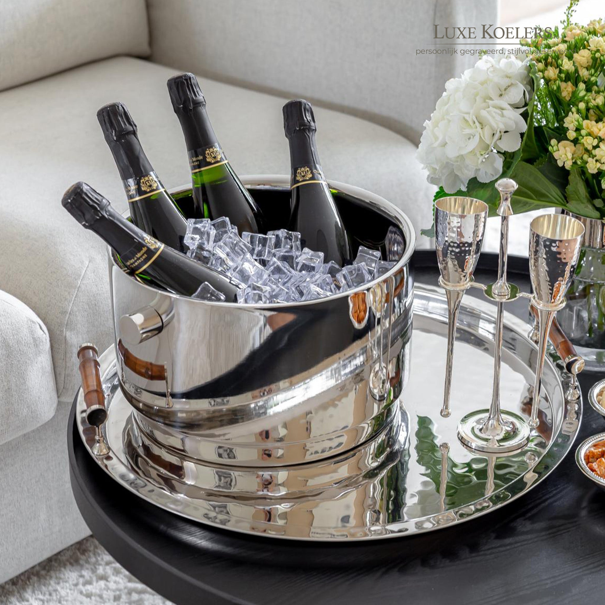 vier champagneflessen in een zilveren champagnekoeler op een zilveren dienblad